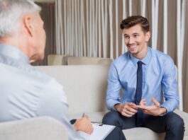 A smiling businessman in a blue suit and shirt receives advice from an ethical debt collector
